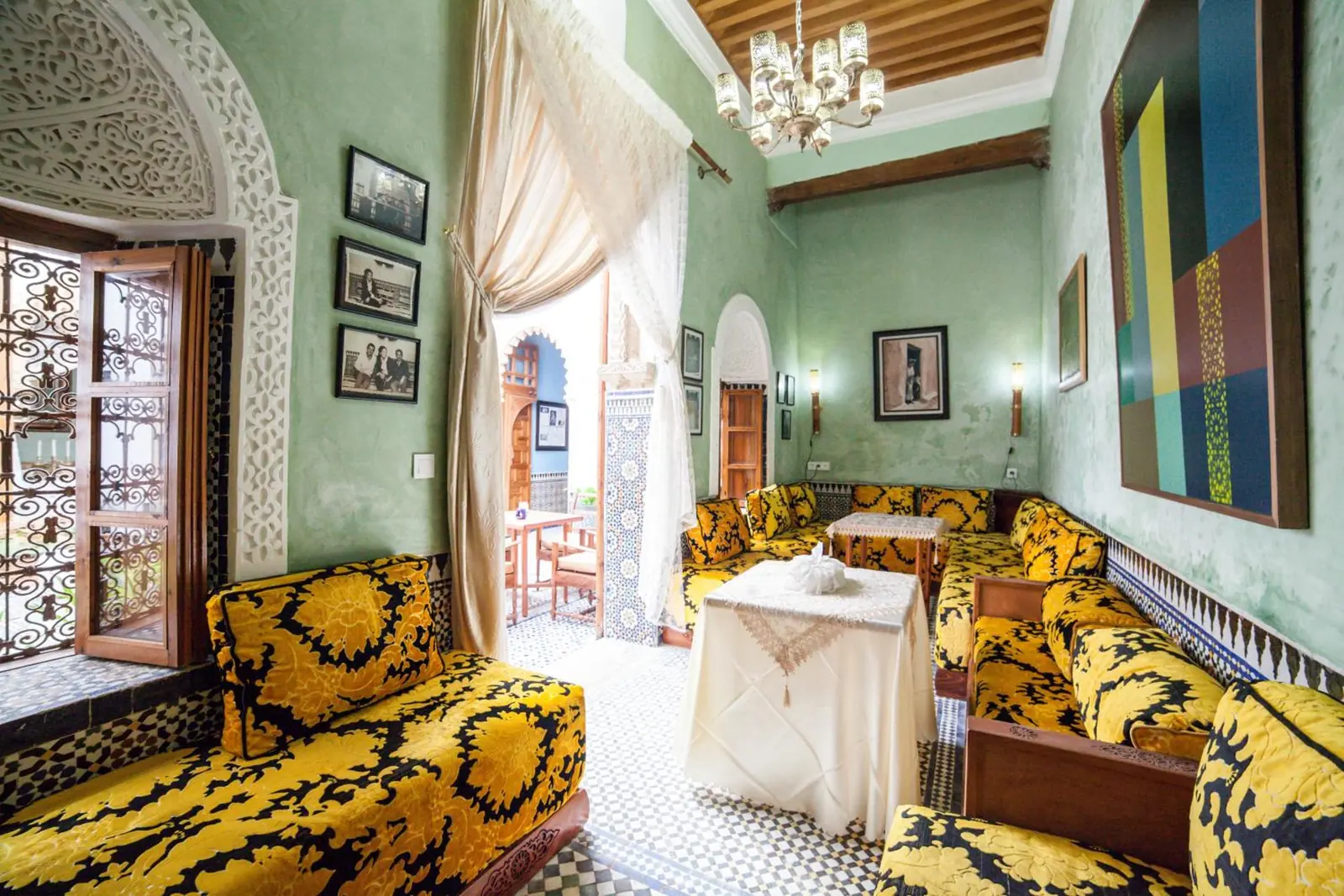 Le salon aux murs verts, lustre et banquettes