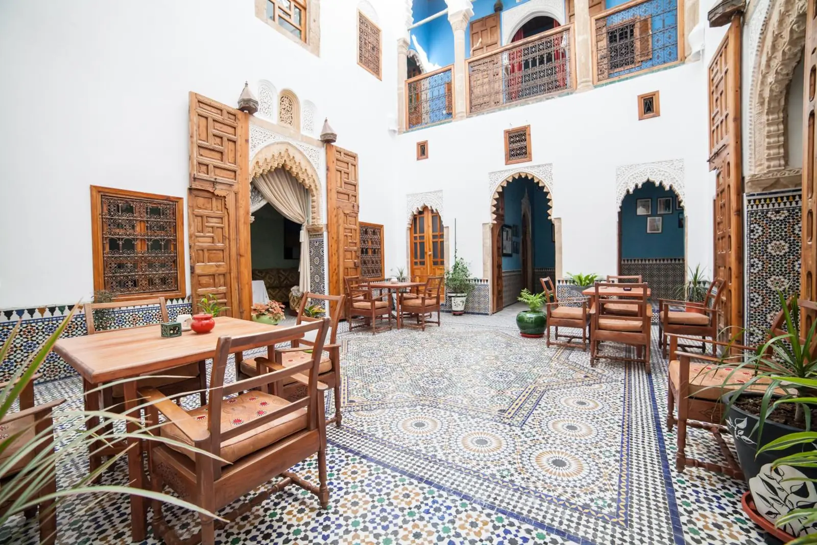 Le patio et ses tables, la galerie bleue au-dessus