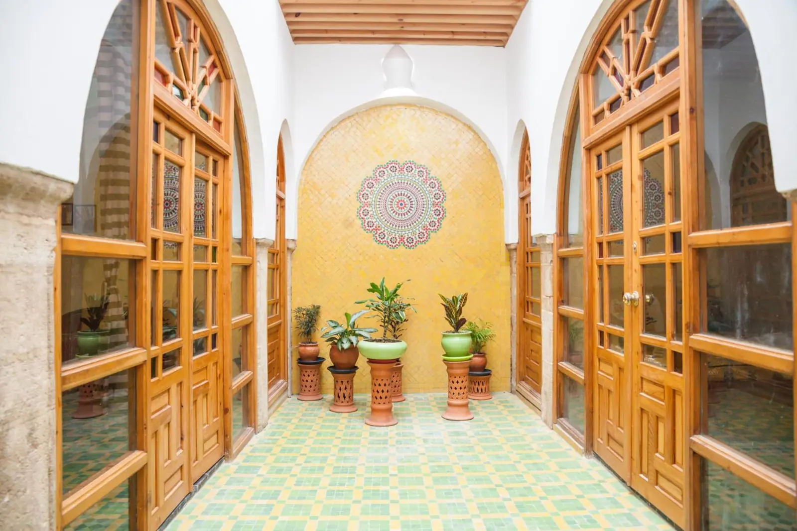 Un petit patio aux murs jaunes, portes vitrées et plantes