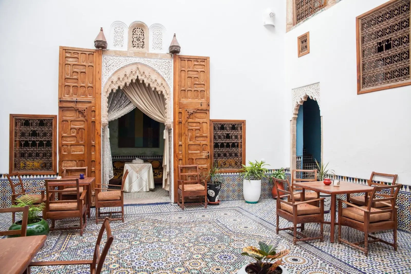 Le patio, le portail en cèdre sculpté et les tables du petit-déjeuner