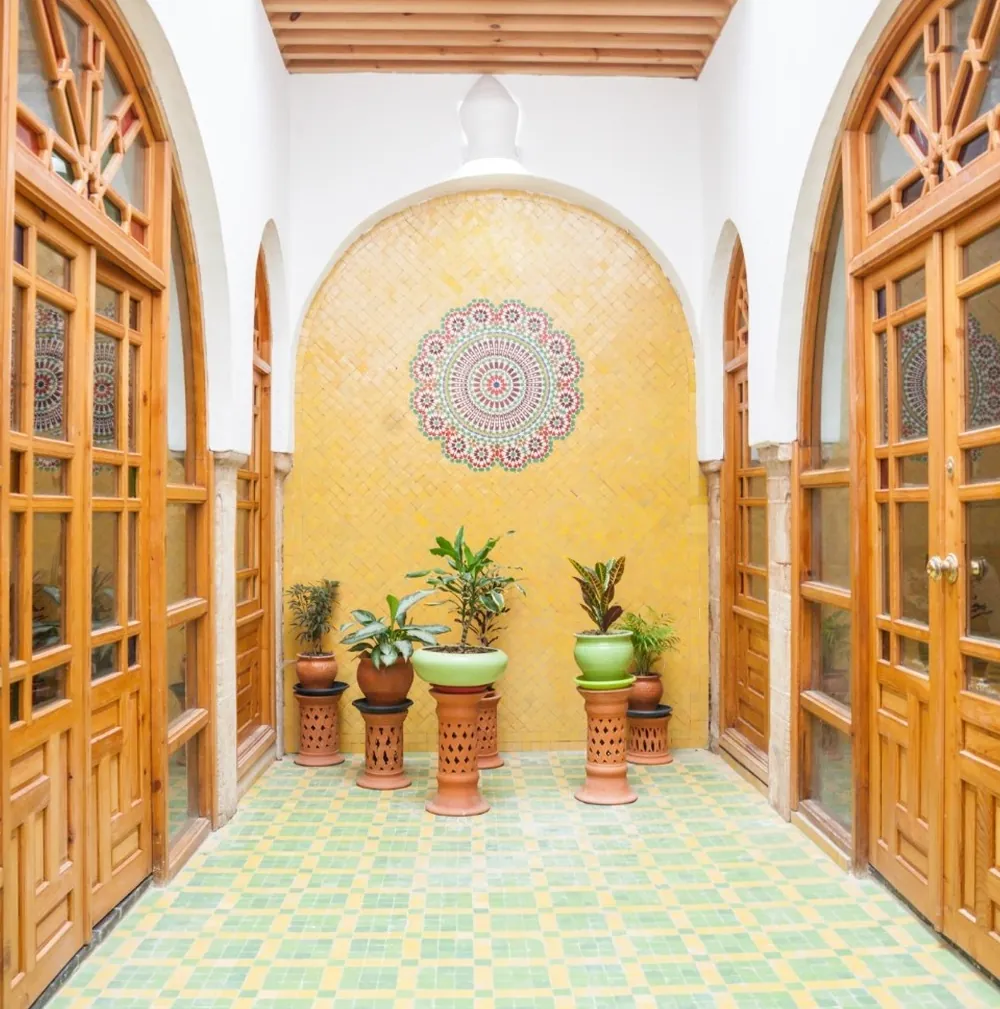 Un petit patio aux murs jaunes, portes vitrées et plantes