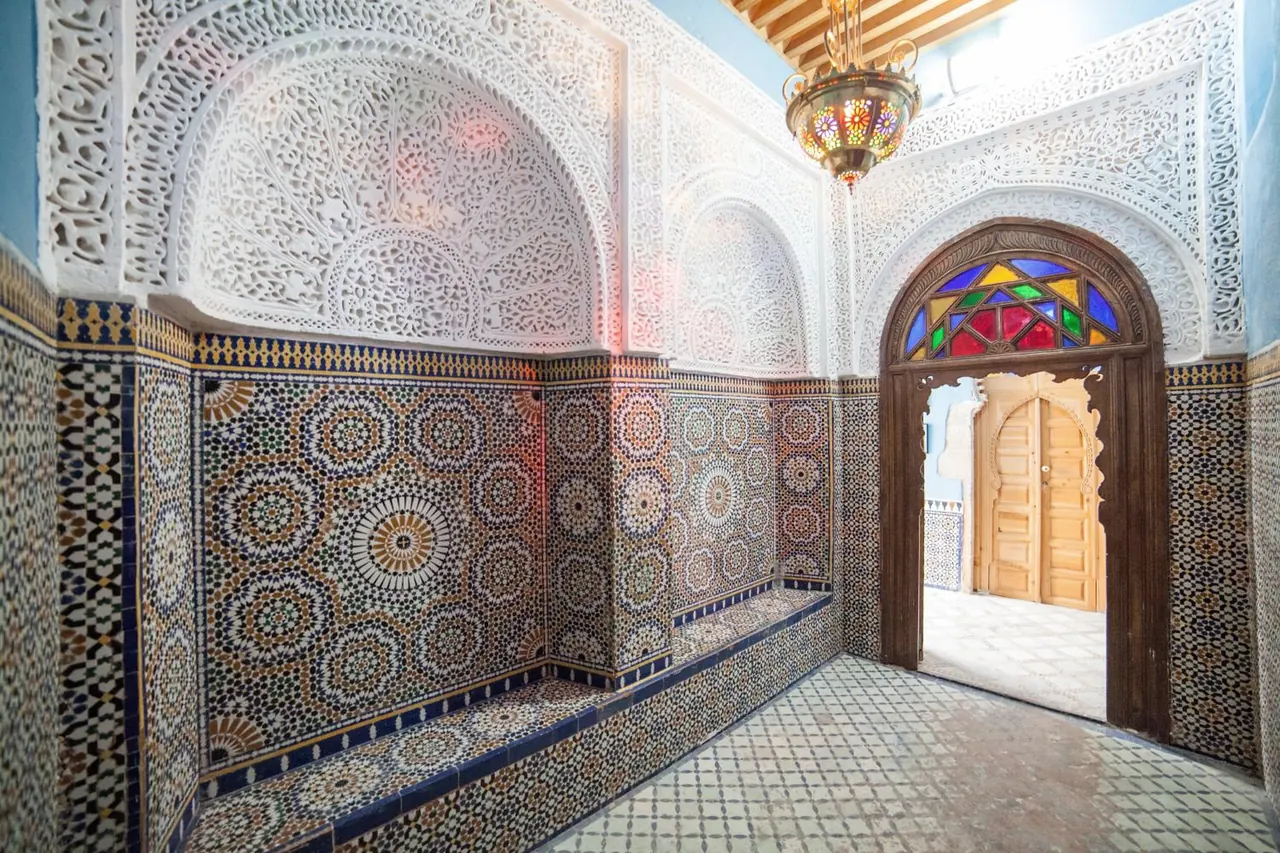 Le vestibule d’entrée : plâtre sculpté, banquette en zellige et porte au vitrail